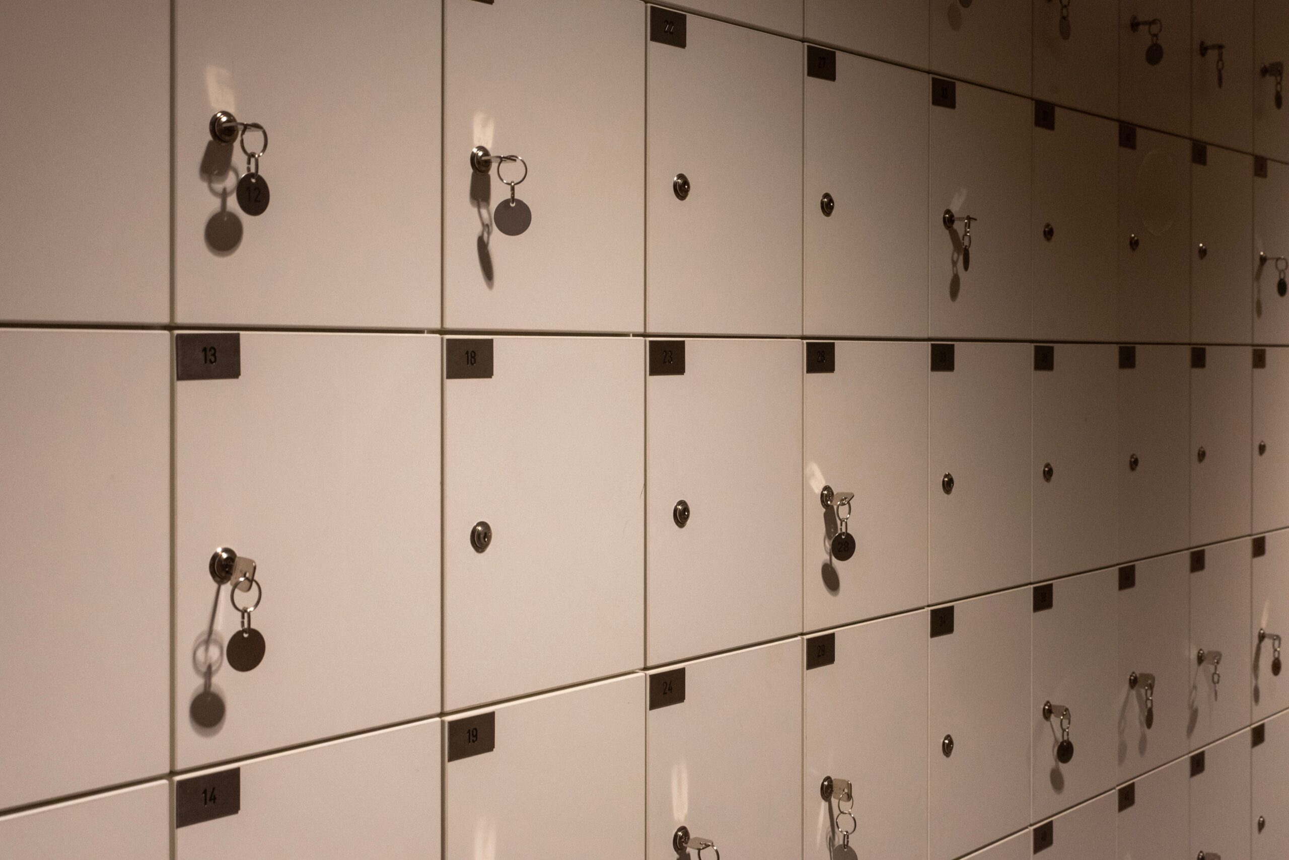 Dimly lit rows of lockers with keys, creating a geometric pattern in an indoor setting.